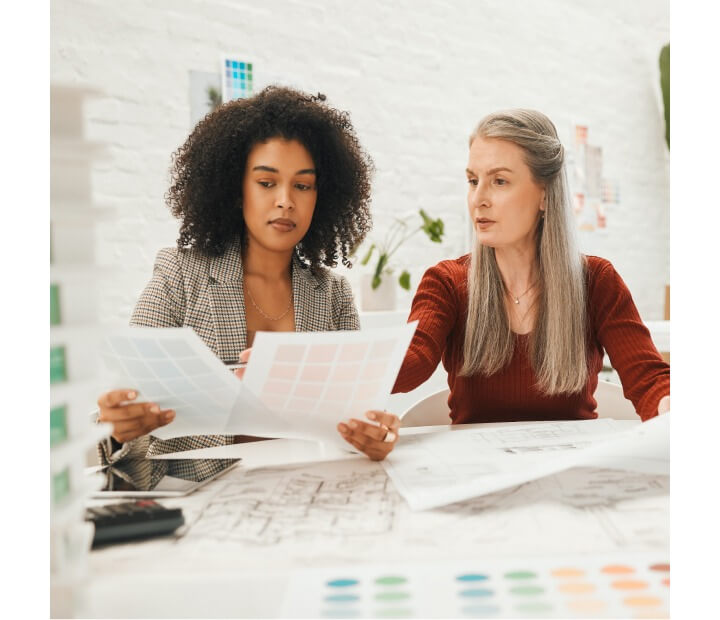 Architect and her client review plans and color swatches at a desk in boutique office environment 